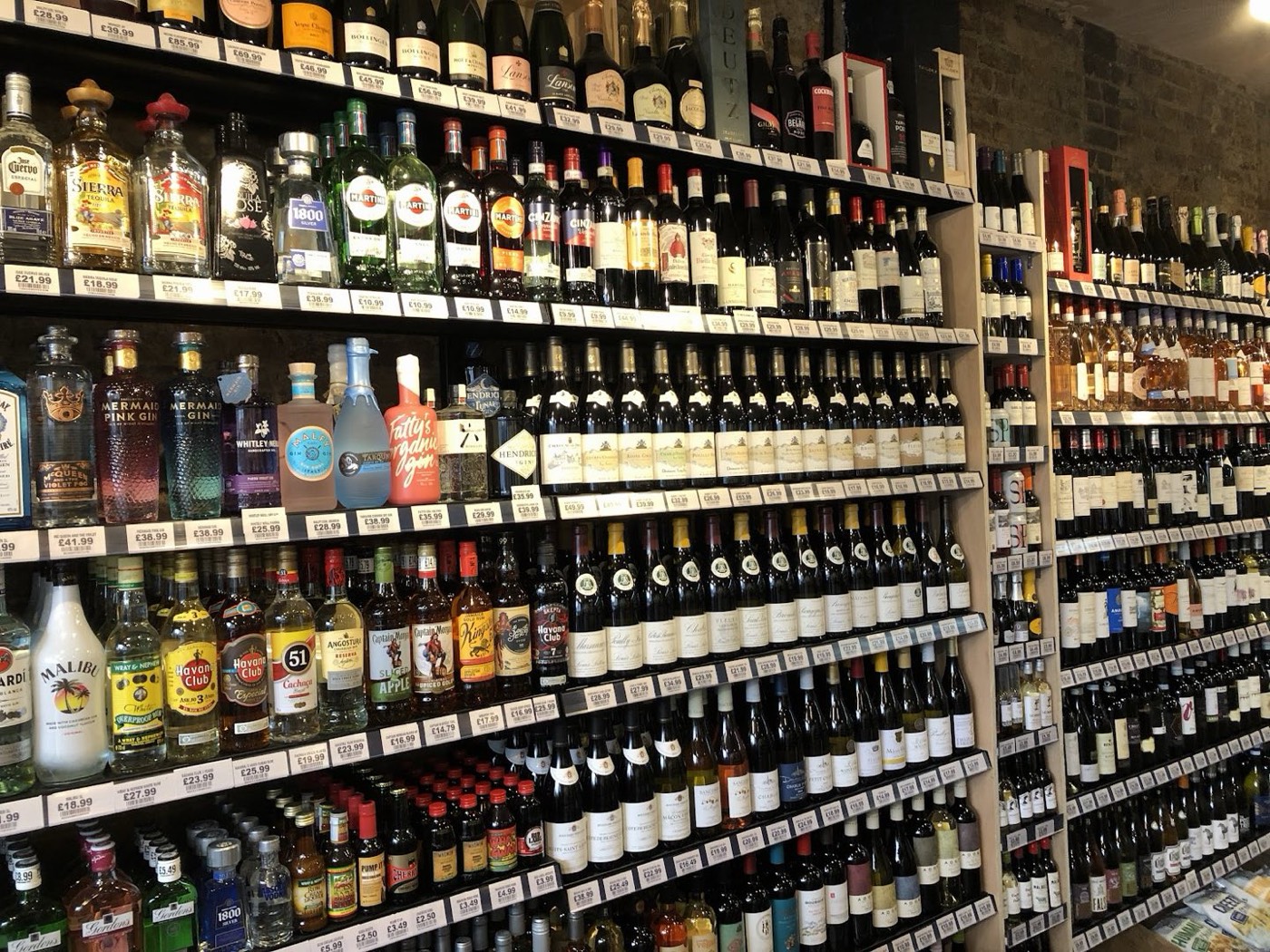 The full wall of wine and spirits at Vintage Bottle, bottles floor to ceiling with shelf-edge prices